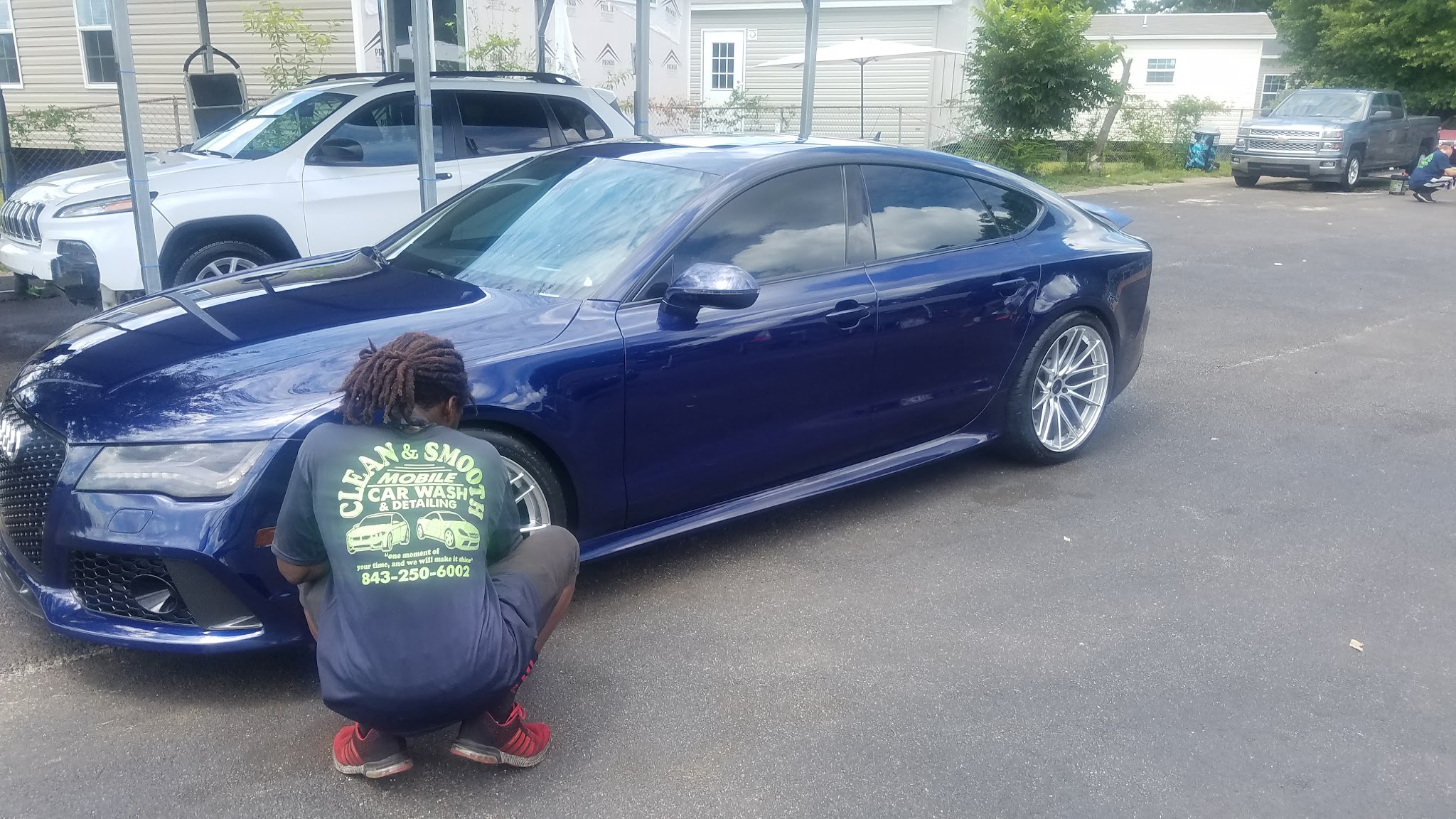 One of our crew detailing the wheel of a blue Audi, wearing our branded shirt